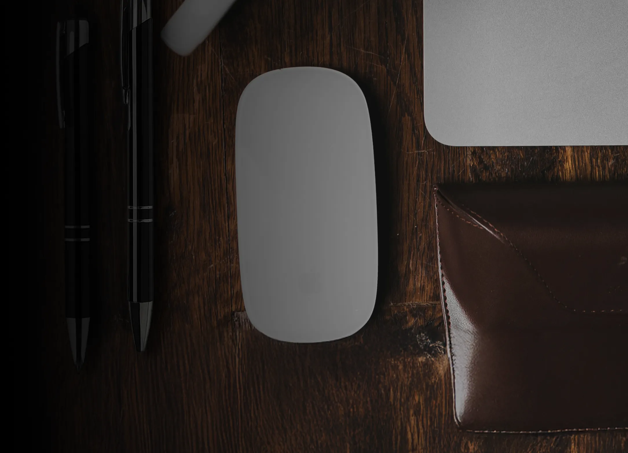 A desk with a mouse, keyboard and a leather wallet.