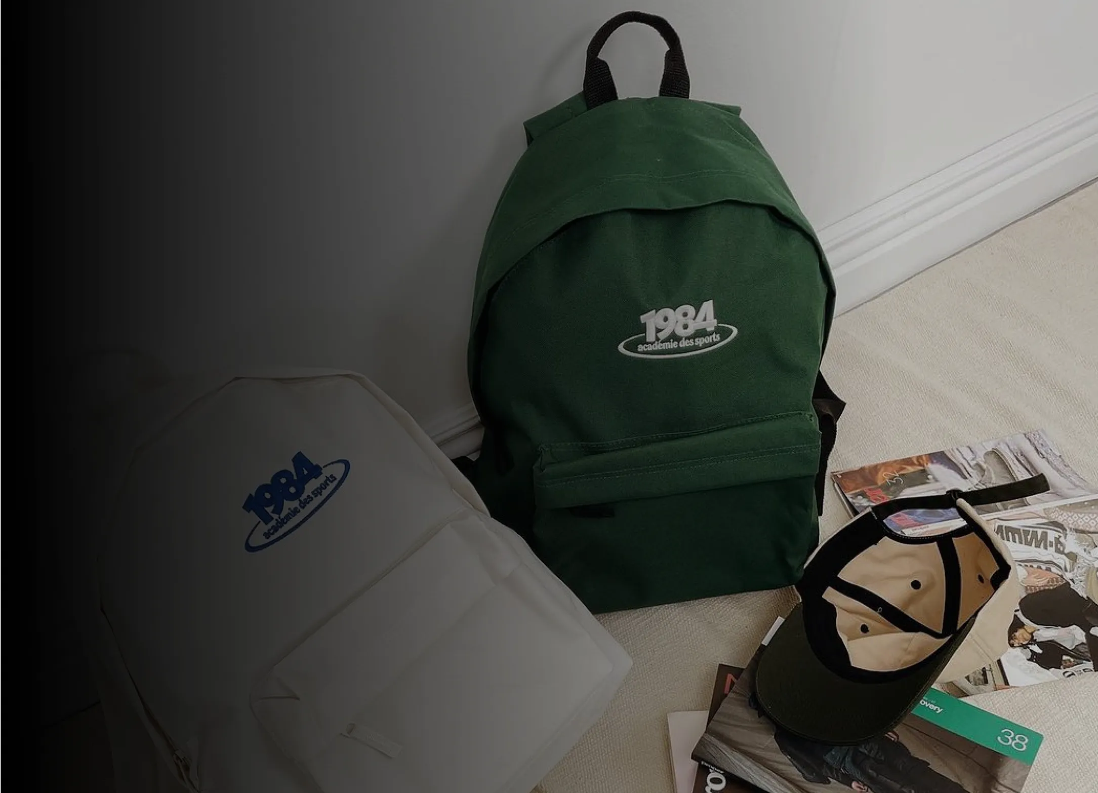A green backpack sitting on the floor next to magazines.